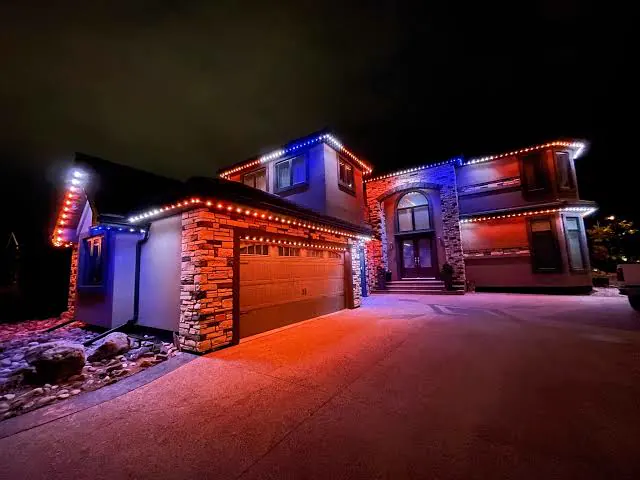 Two-story home with orange and blue lights outlining the garage and rooflines
