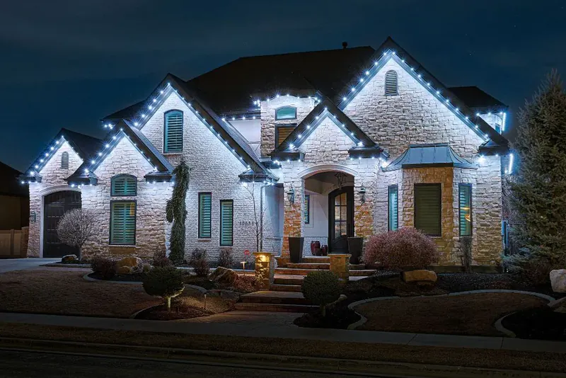 Stone home lit in cool white and icy blue along every gable